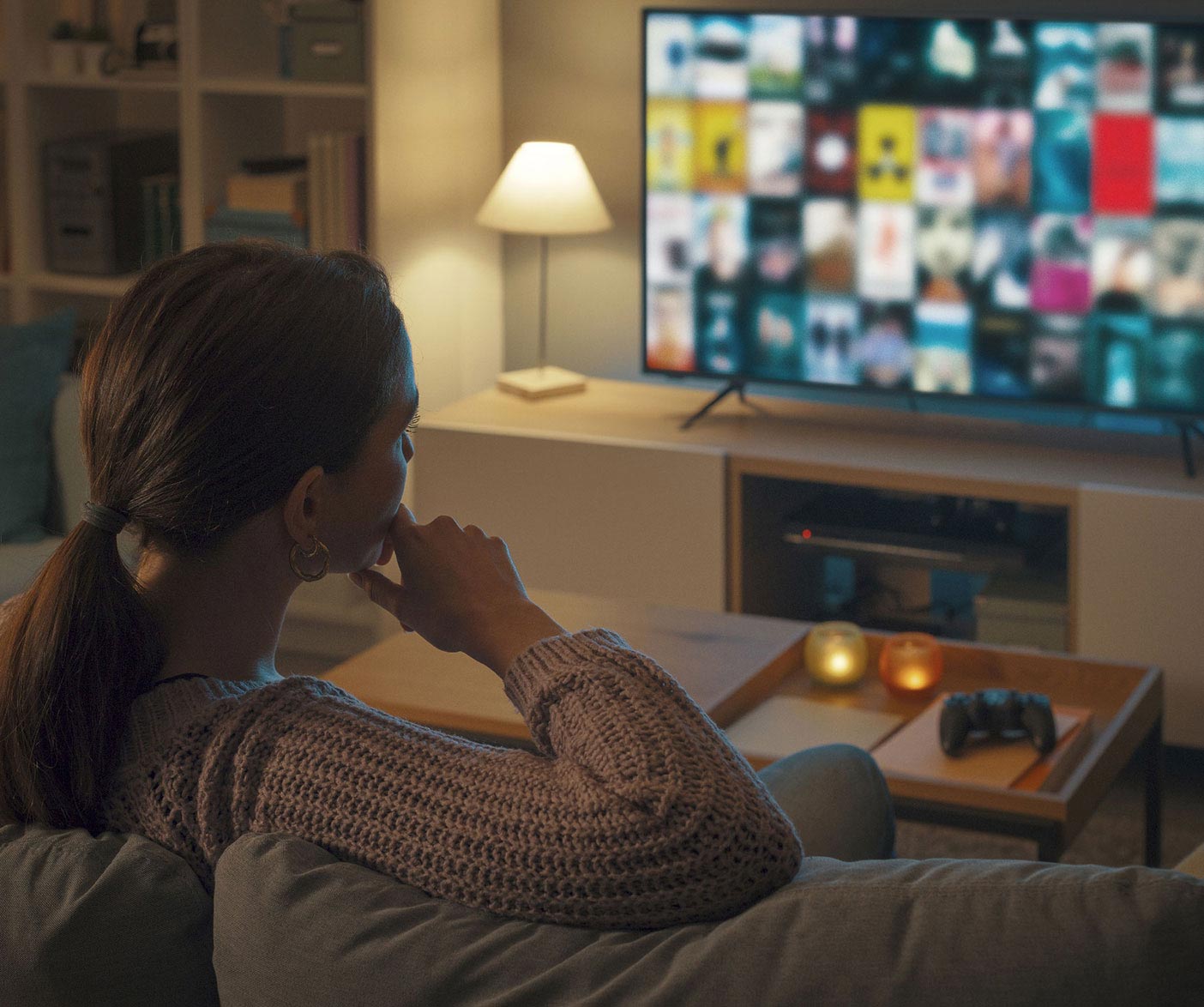 Woman sits on couch watching television.