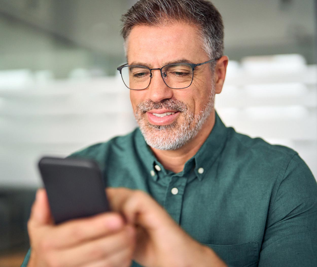 A man smiles as he scrolls on his phone.