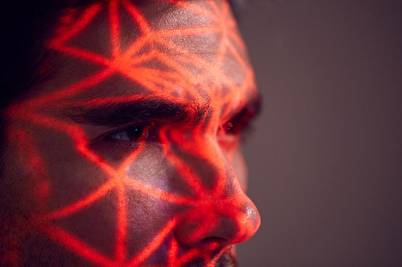 Red lines of light scan a man's face.