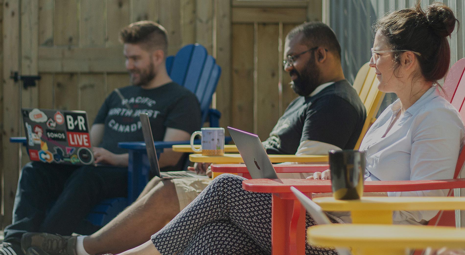 A team of people work together outdoors in the sun on the REDspace deck.