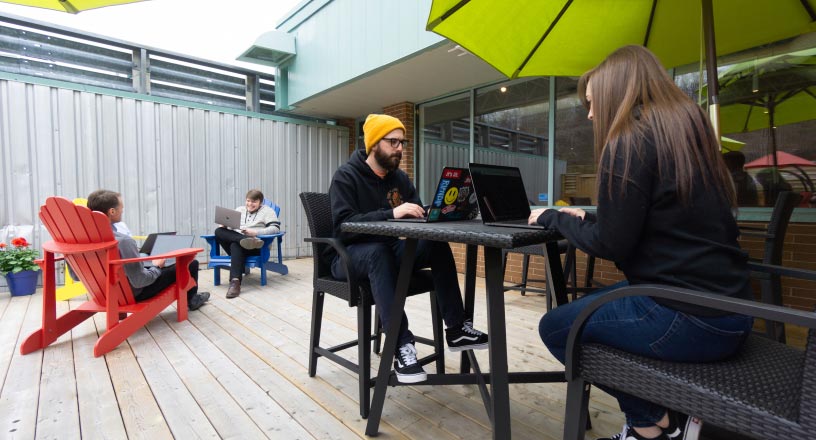 Multiple REDspace team members work outside on the office deck during the Summer.