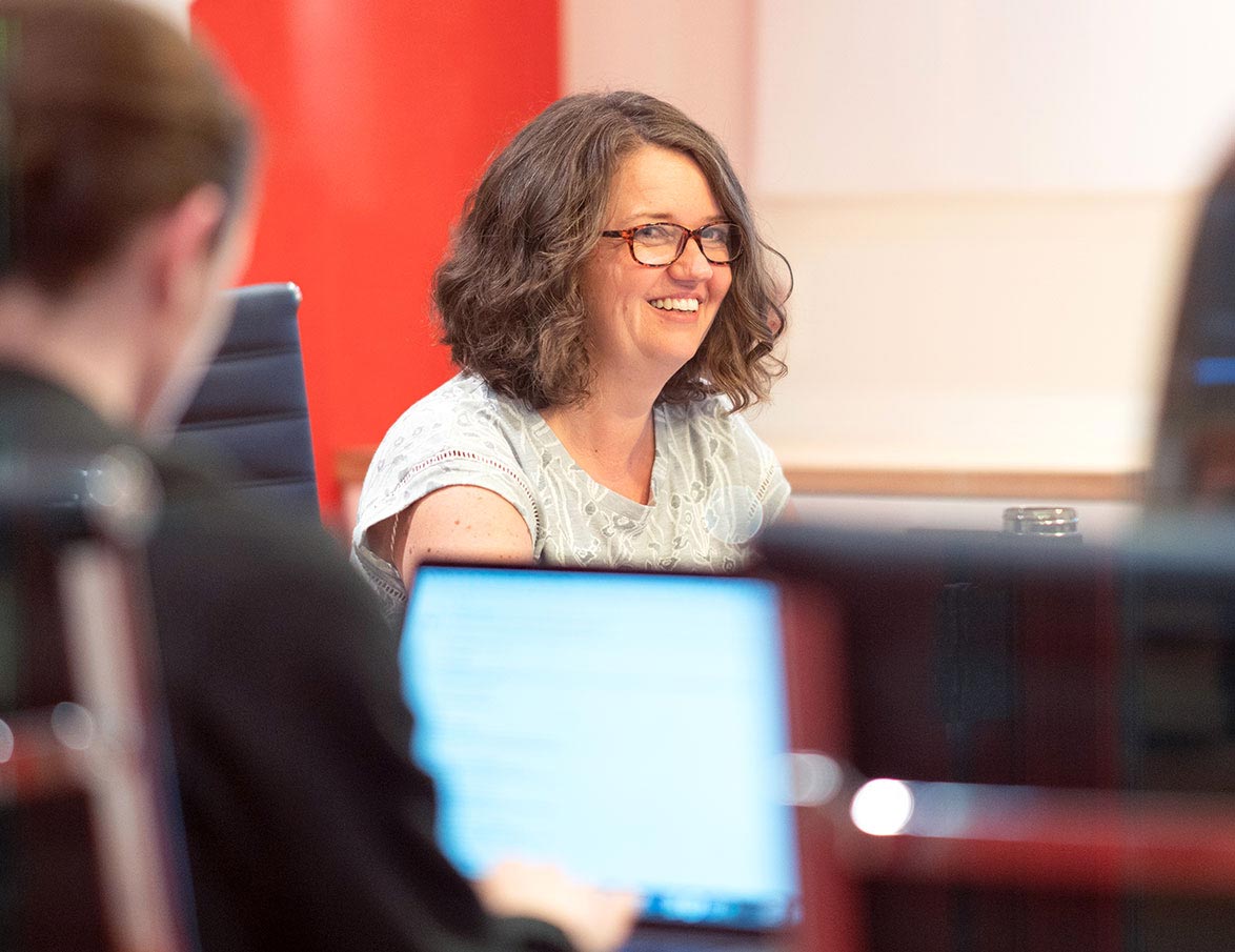 A female REDspace employee smiles during a boardroom meeting.