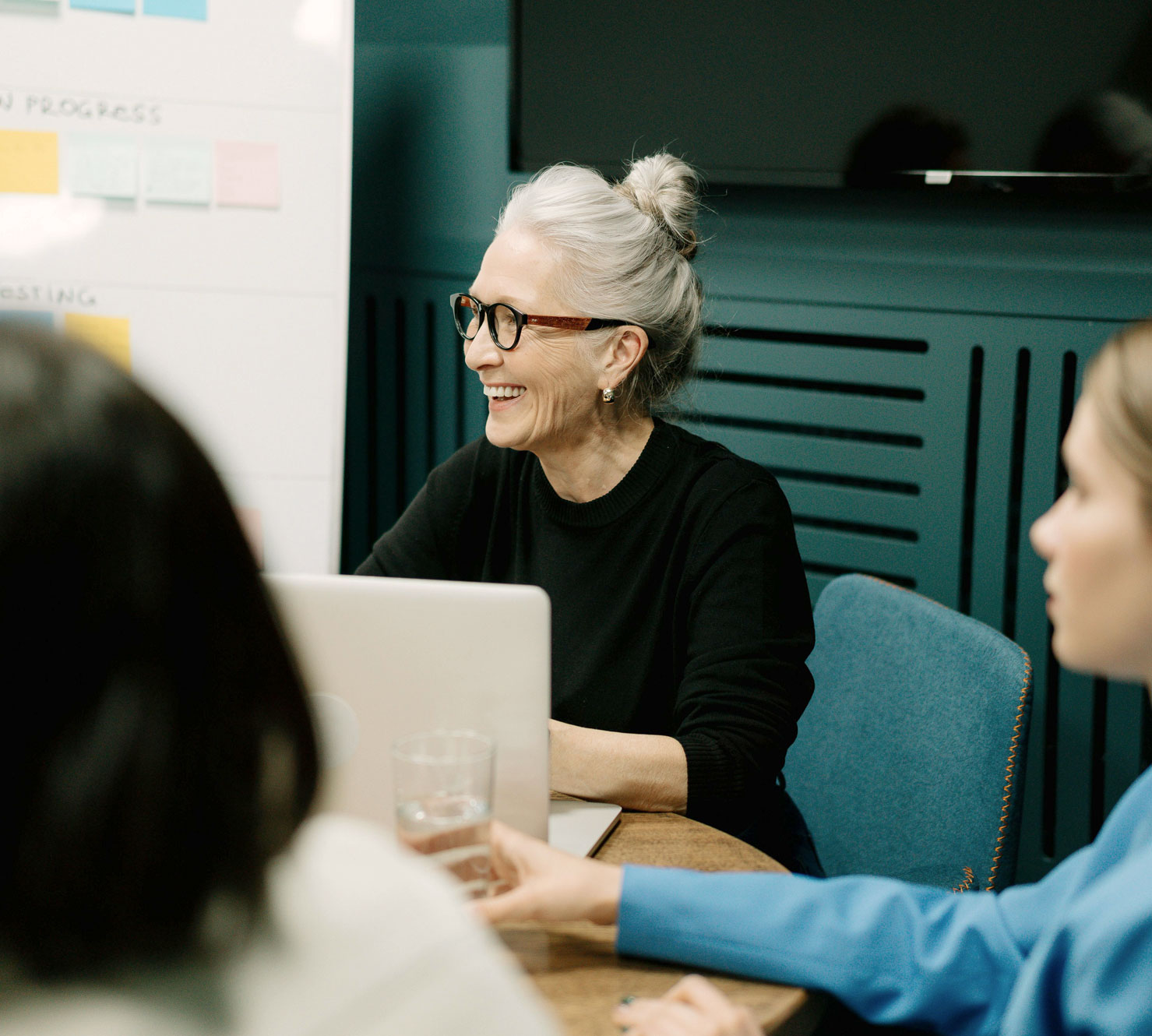 A woman smiles in her seat at a table during a productive work meeting.