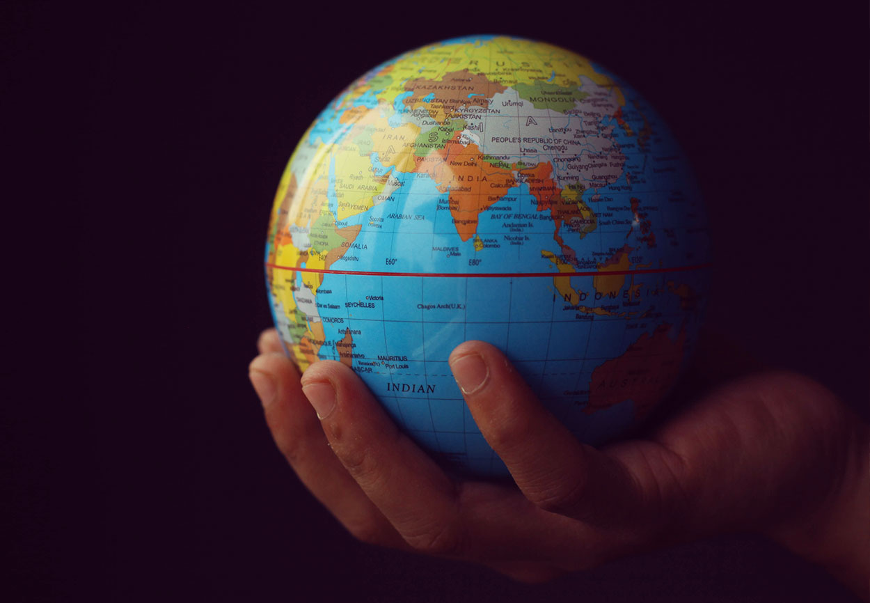 A hand holds a small globe.